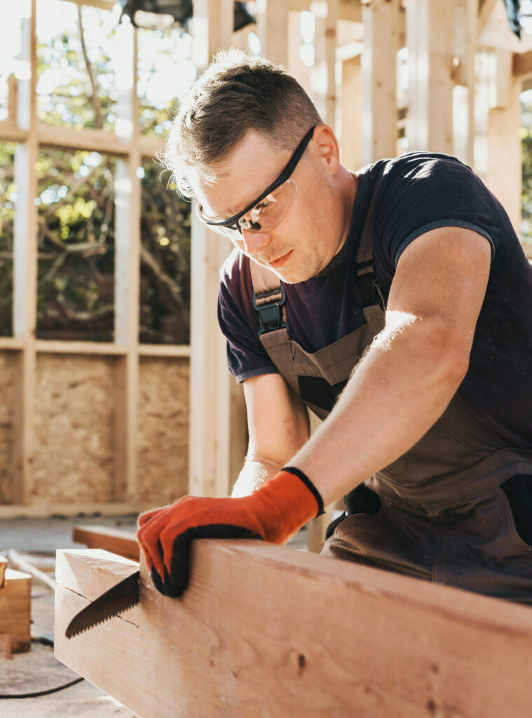 Charpentier découpant une poutre en bois avec précision sur un chantier de construction.