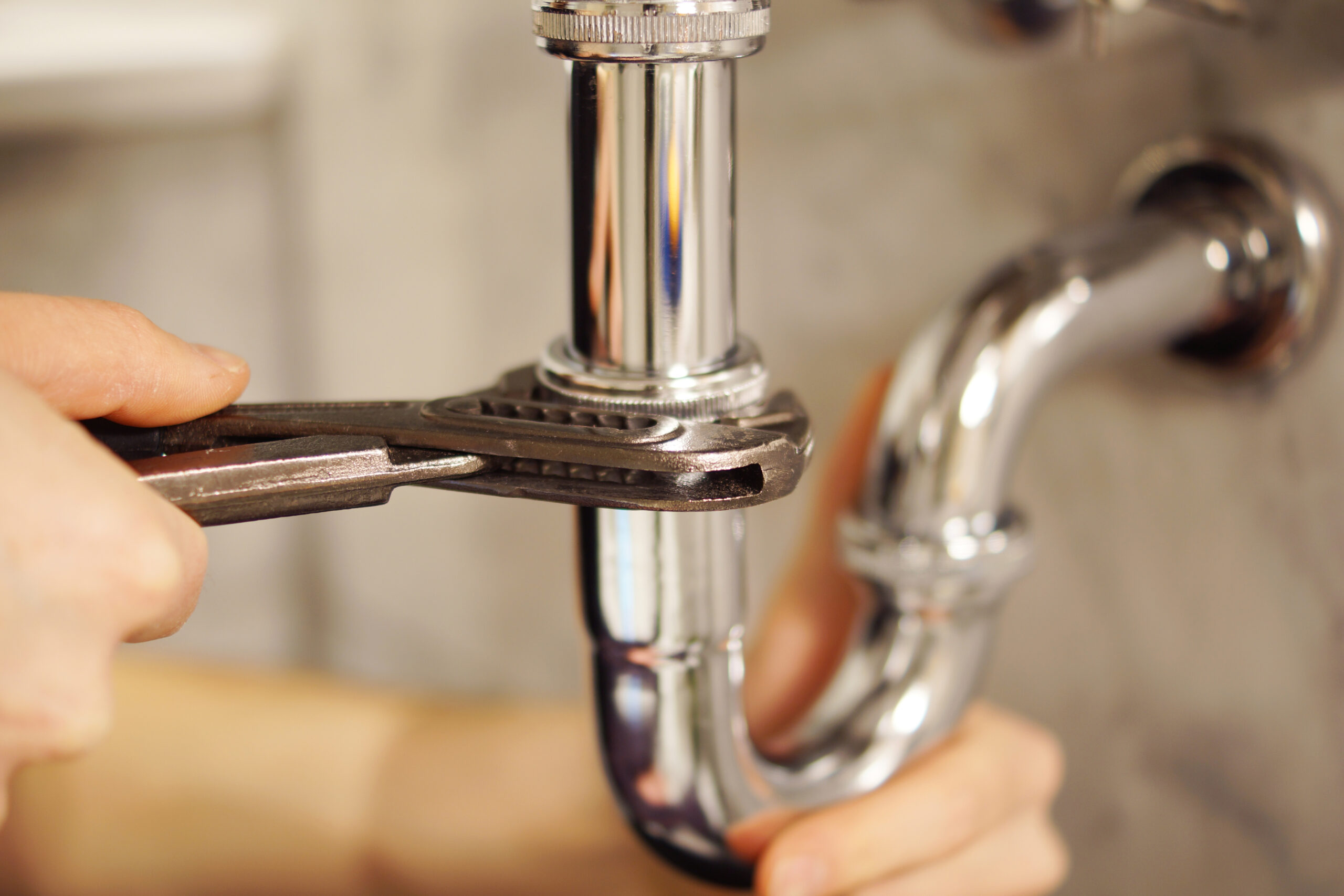 Plombier installant un siphon sous un évier lors d'une intervention de plomberie.