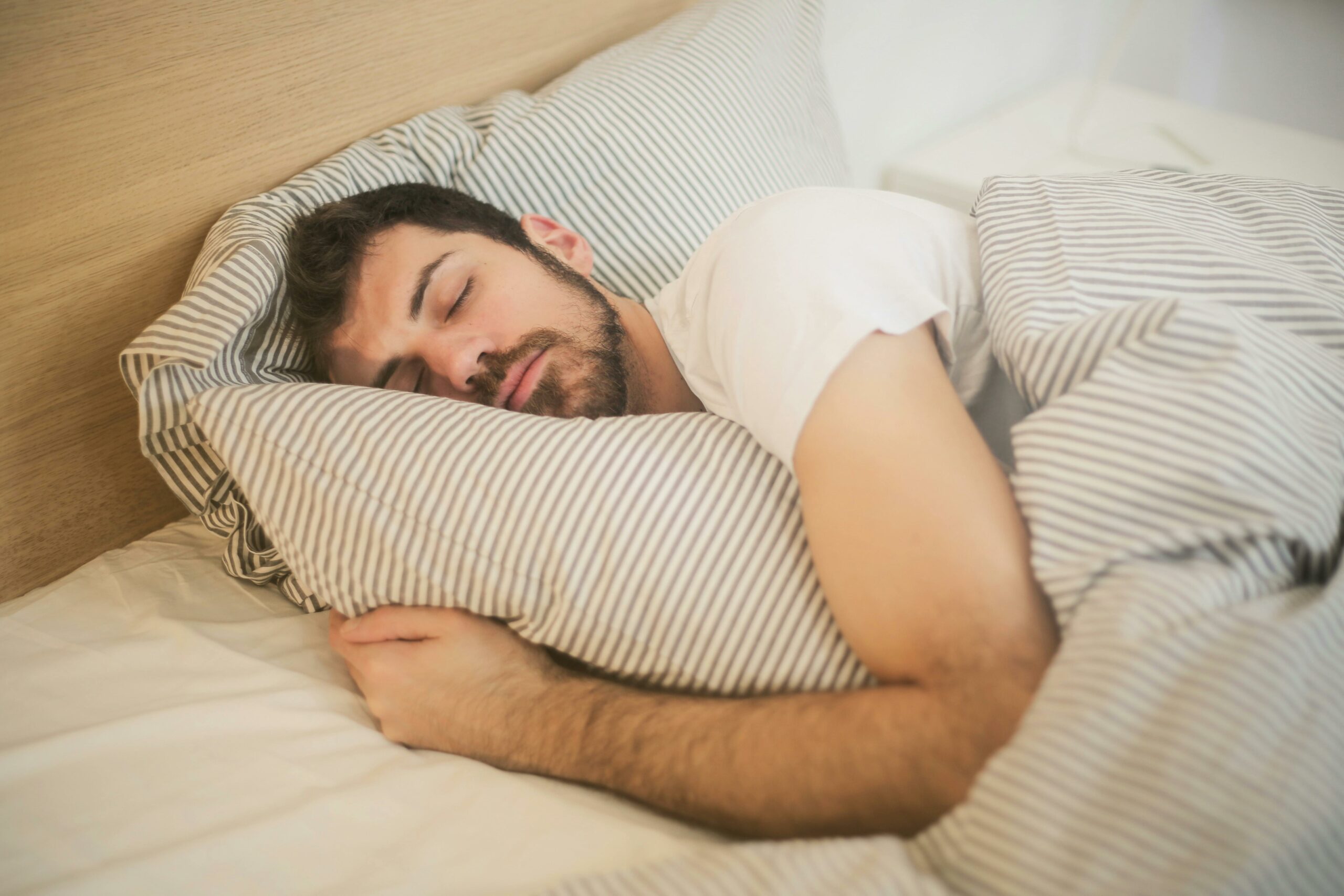 Homme endormi paisiblement dans un lit, bénéficiant d’un air intérieur sain grâce à une VMC double flux