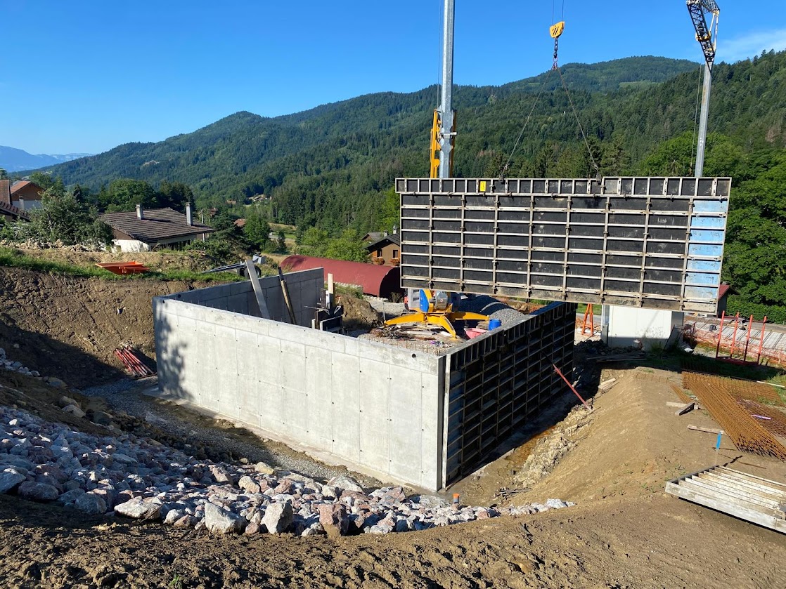 Montage des murs en béton à l’aide de coffrages, sur un terrain en pente à Saxel.