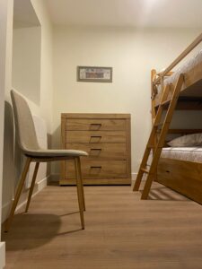Chambre rénovée dans un appartement à Thonon avec parquet clair, lits superposés et commode en bois.