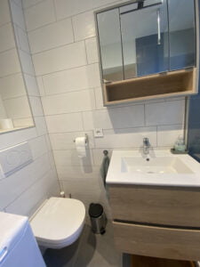 Salle de bains rénovée à Thonon avec meuble vasque moderne et murs carrelés blancs.