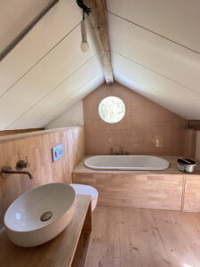 Salle de bain sous combles rénovée avec baignoire encastrée et décoration en bois naturel.