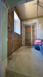 Travaux dans une chambre à Thonon avec murs isolés et installations électriques en cours.