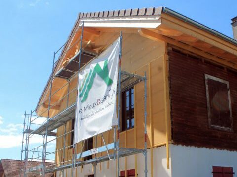 Installation d’un nouveau revêtement de façade sur une maison en rénovation avec échafaudage et bannière Le MieuxDisant.