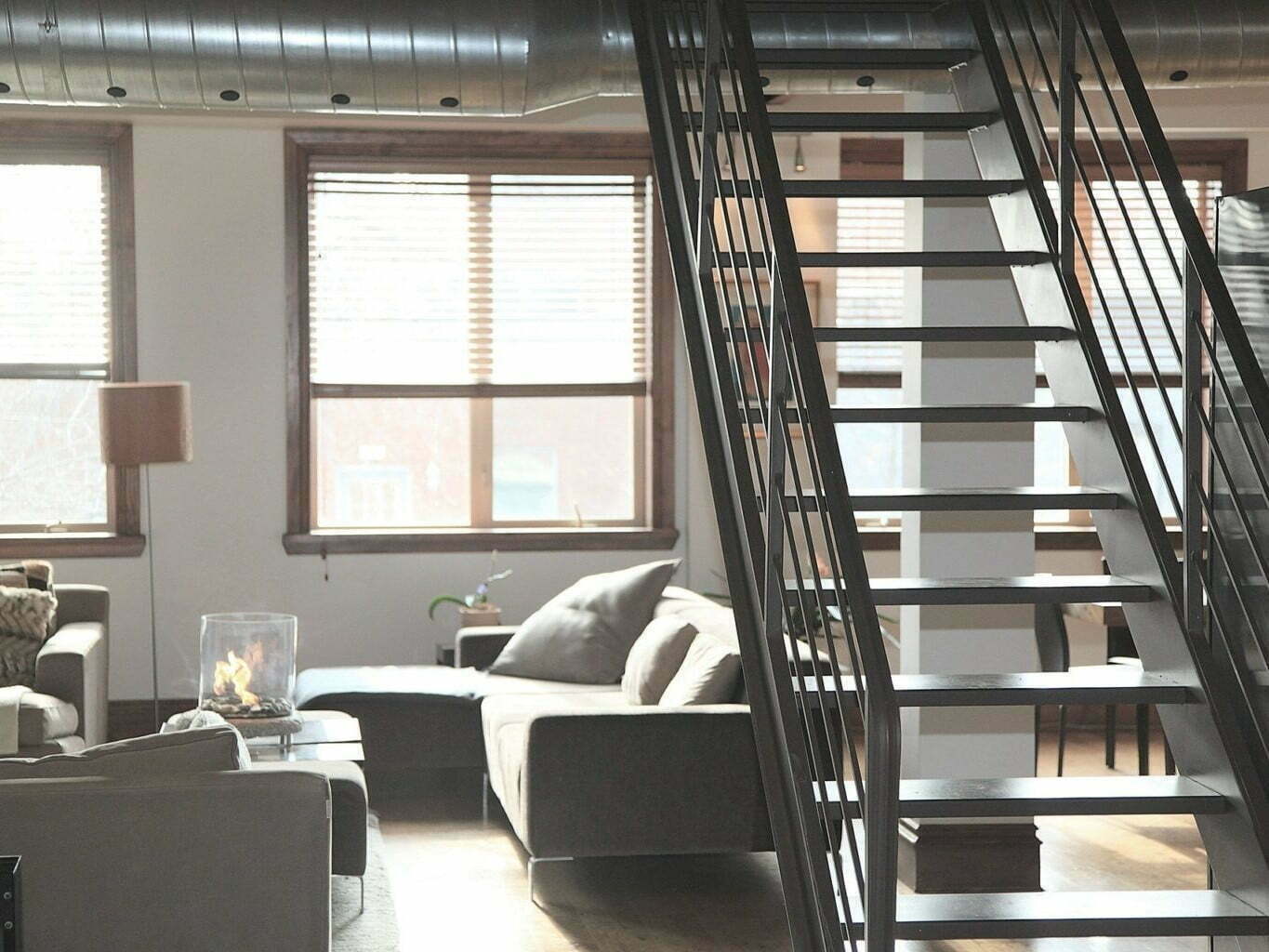 Escalier central en métal noir dans un intérieur style loft industriel.