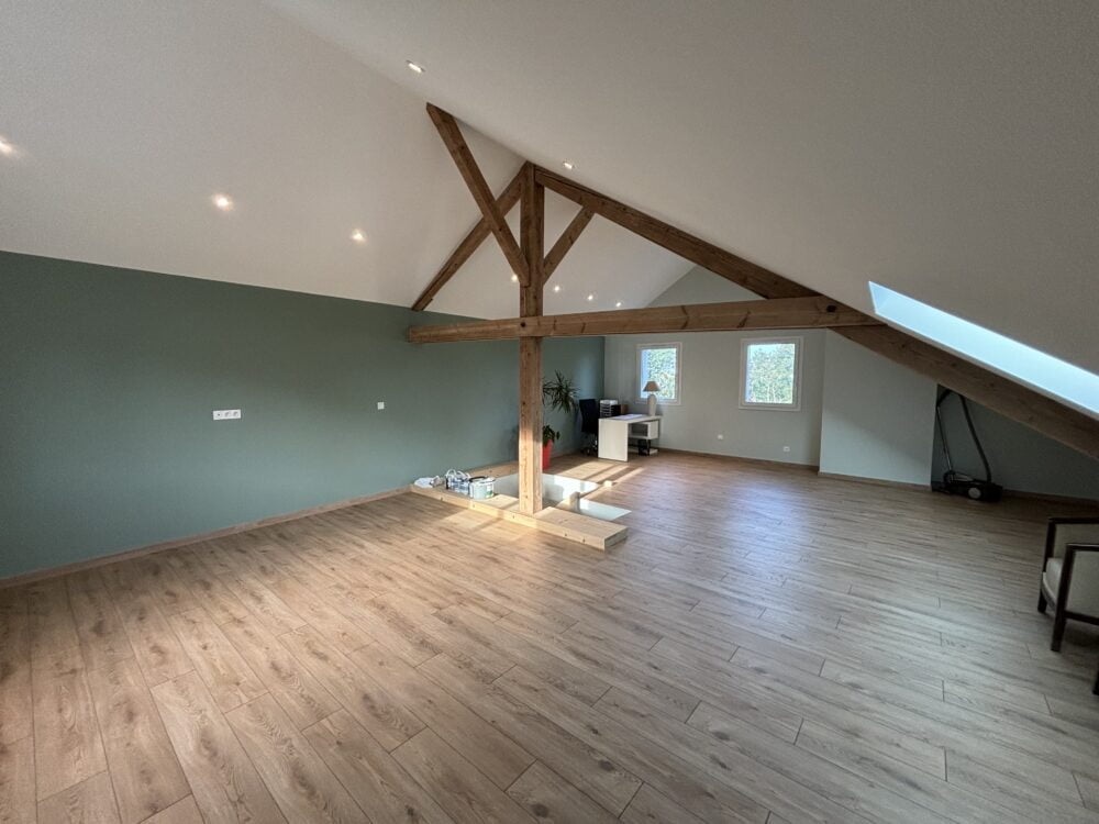 Combles aménagés à Bons-en-Chablais avec parquet bois et poutres apparentes.