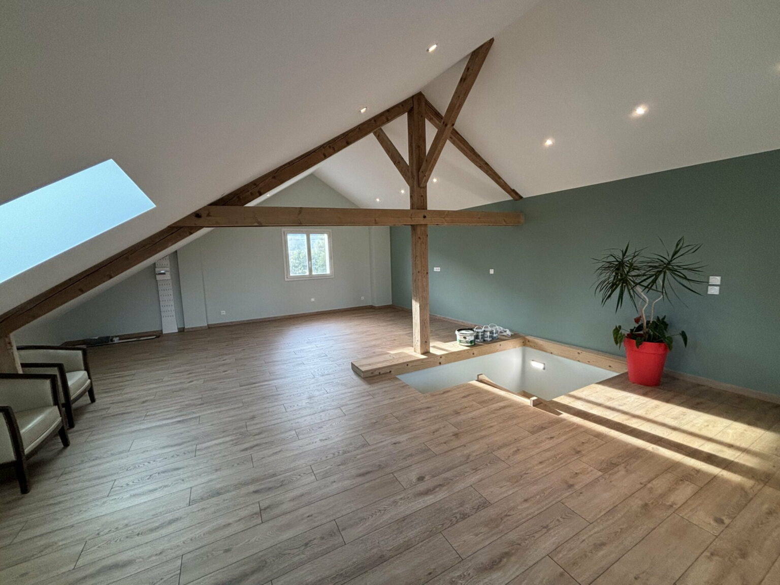 Combles aménagés avec parquet bois clair et poutres apparentes à Bons-en-Chablais.