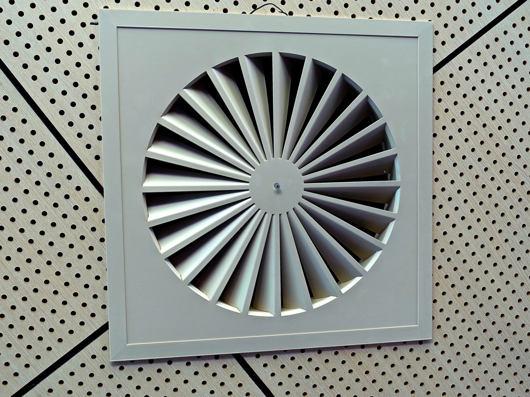 Gros plan sur une grille de ventilation VMC double flux installée au plafond.