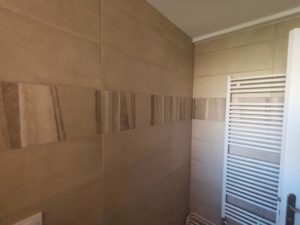 Salle de bain rénovée à Thonon avec carrelage moderne beige et détails décoratifs.