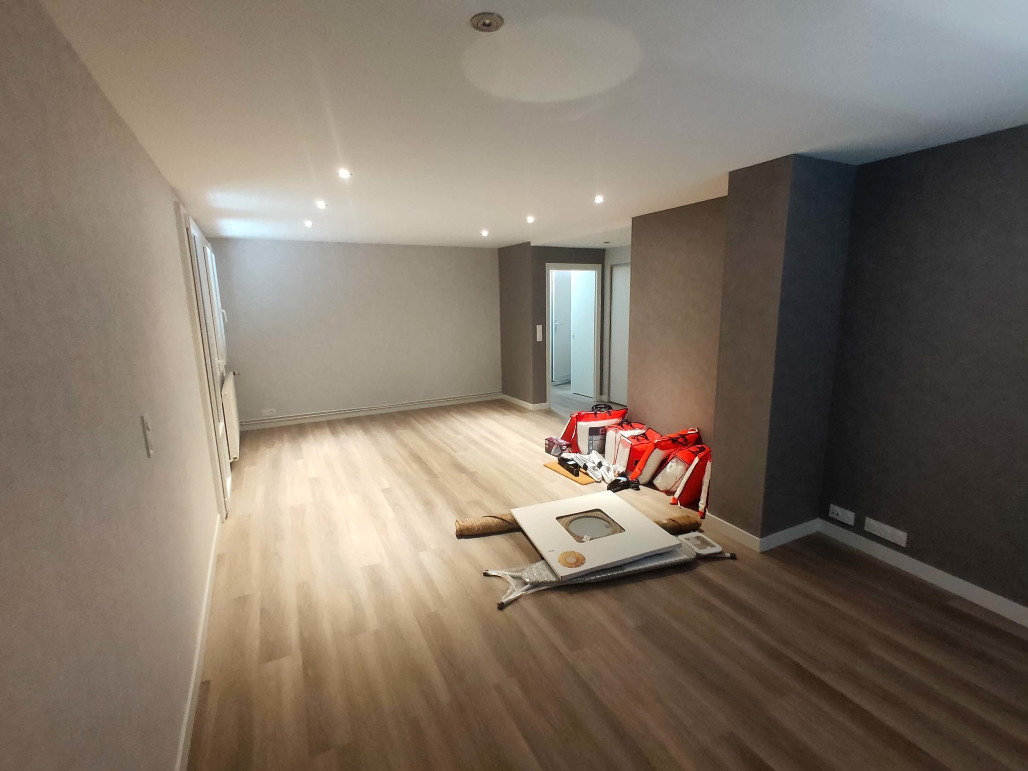 Salon rénové d’un appartement à Thonon avec parquet clair, murs modernes et éclairage encastré.