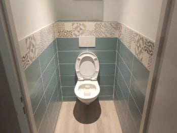 Toilettes rénovées à Thonon avec carrelage bleu et faïence décorative.