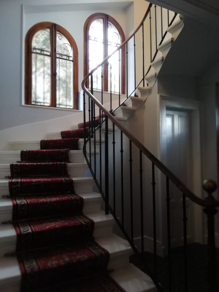 Escalier rénové avec tapis rouge et rampe en fer forgé dans une maison à Évian.
