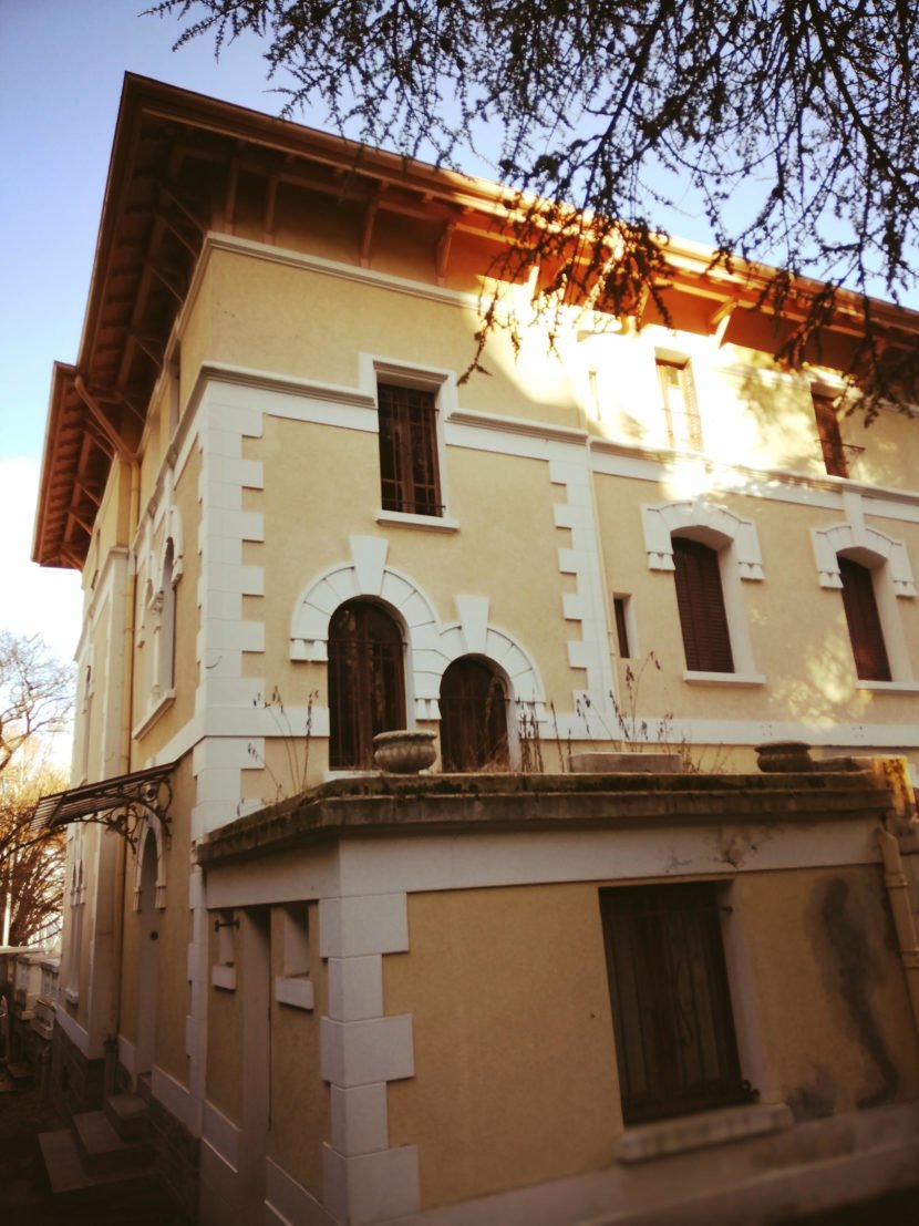 Façade d'une maison ancienne rénovée à Évian avec détails architecturaux classiques.