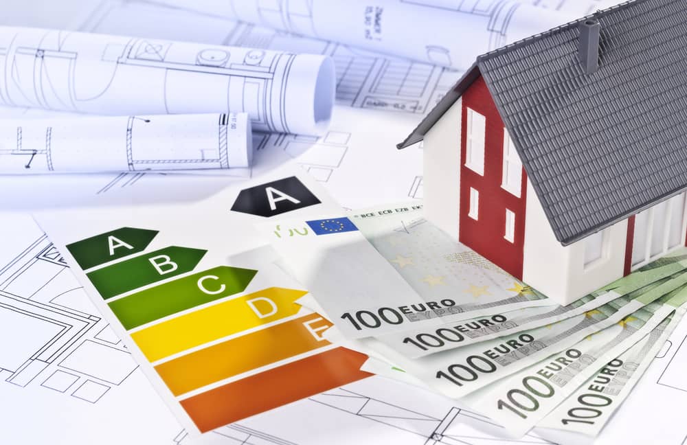 Maquette de maison avec billets d’euros et étiquette DPE illustrant le lien entre audit énergétique et économies