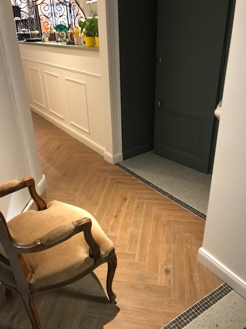 Coin couloir avec fauteuil vintage et parquet en chevron dans une crêperie rénovée à Évian