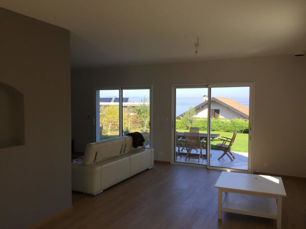 Salon avec double baie vitrée offrant une vue dégagée sur le jardin à Évian