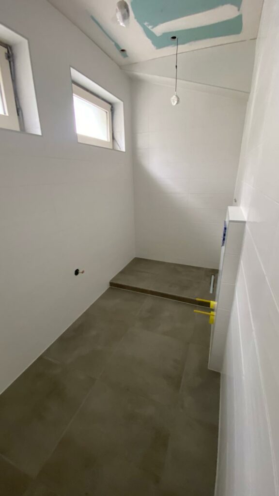 Salle de bains rénovée à Évian avec zone de douche en estrade et fenêtres hautes