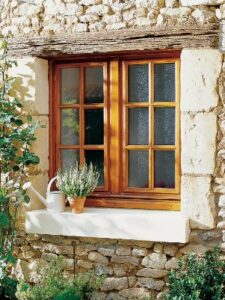 Fenêtre en bois installée sur une maison en pierre, alliant performance énergétique et charme traditionnel
