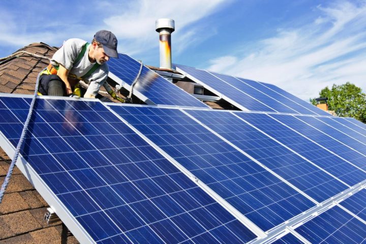 Artisan installant des panneaux solaires sur le toit d'une maison