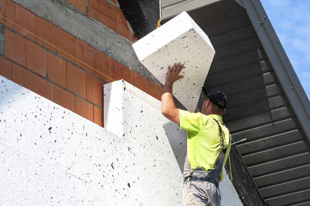 Pose de panneaux isolants rigides sur une façade en brique dans le cadre d’une ITE