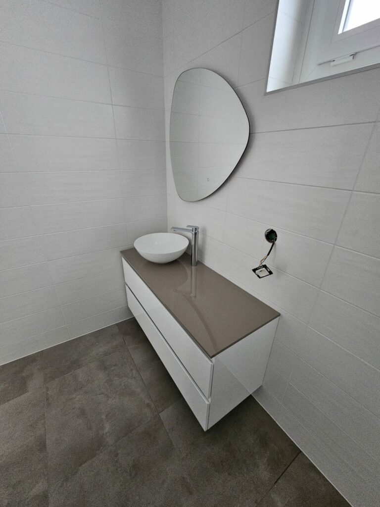 Meuble vasque blanc moderne avec miroir design dans salle de bains rénovée à Évian