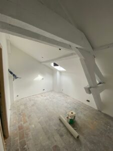 Vue d’une pièce en rénovation dans un studio à Évian avec mur blanc et plafond en pente