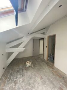 Pièce de vie en travaux avec poutres apparentes avant pose du sol