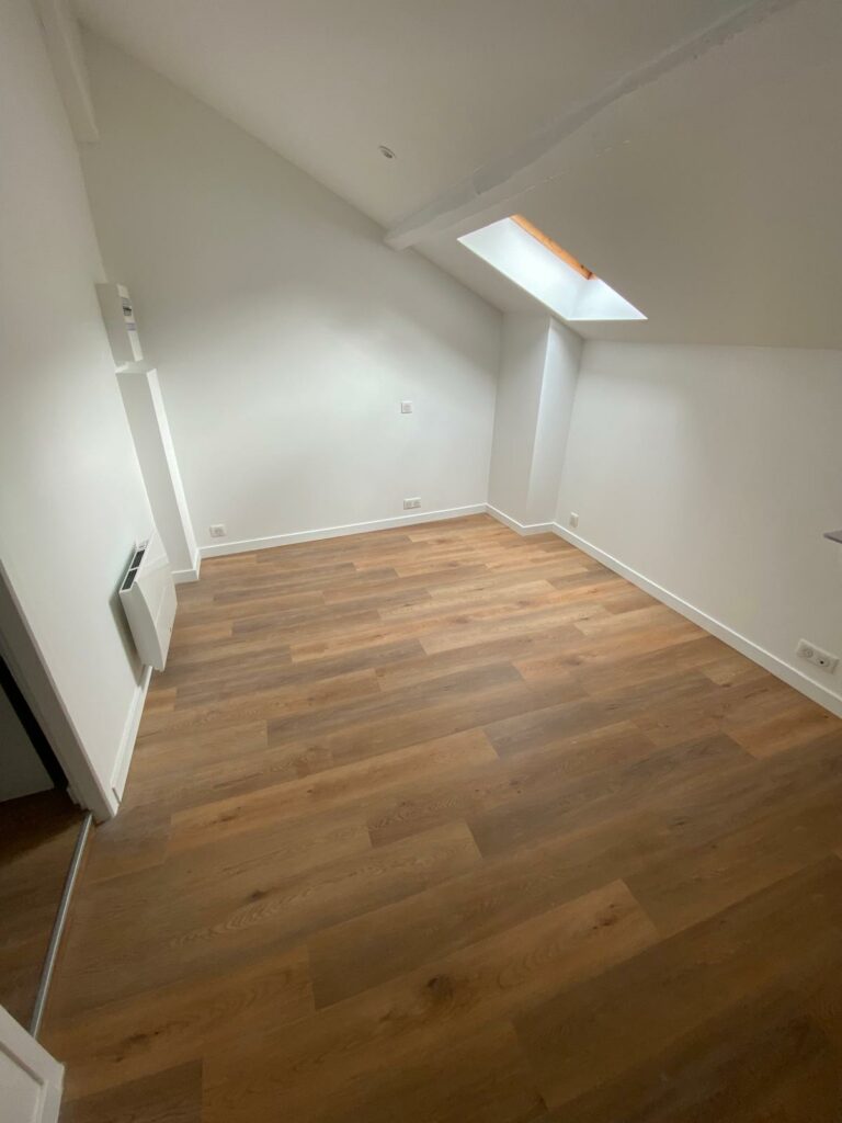 Pièce de vie en travaux avec poutres apparentes avant pose du sol