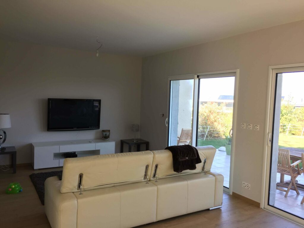 Salon moderne avec baie vitrée récemment posée donnant sur une terrasse à Évian