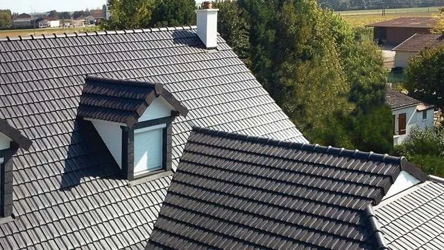 Toiture avec tuiles en béton gris foncé, offrant une bonne inertie thermique