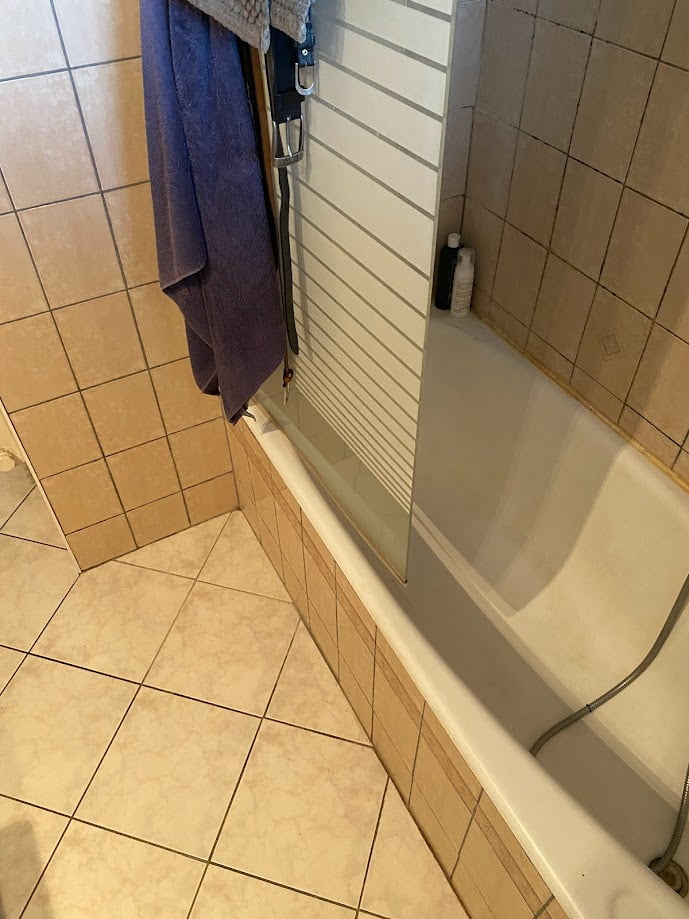 Ancienne salle de bain avec carrelage beige et baignoire avant rénovation