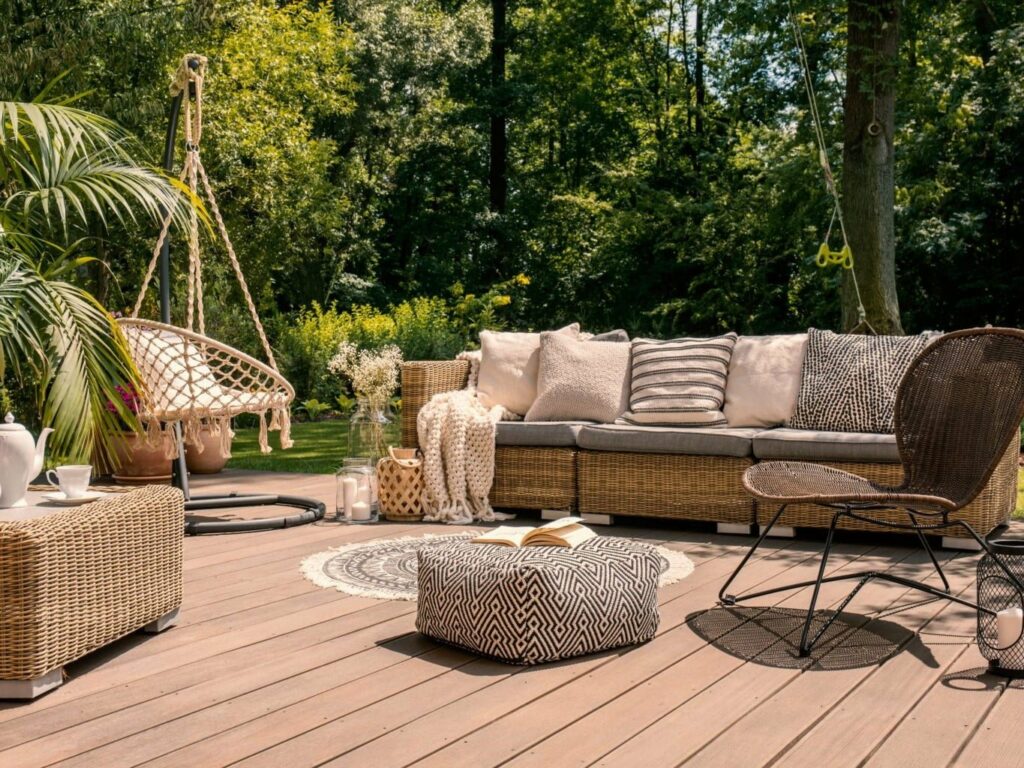 Terrasse cosy en bois, décorée de mobilier en rotin et de coussins aux tons neutres.