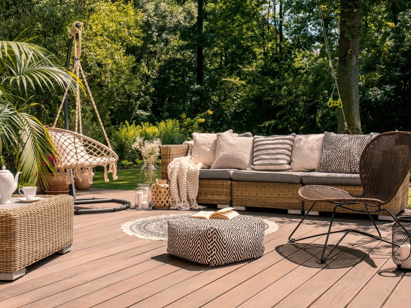 Terrasse cosy en bois, décorée de mobilier en rotin et de coussins aux tons neutres.