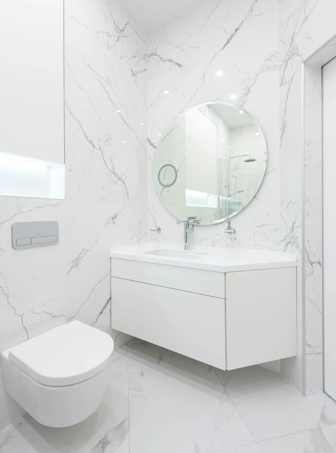 Salle de bains moderne avec sanitaires design en blanc et murs effet marbre, tendance rénovation sanitaire 2024.