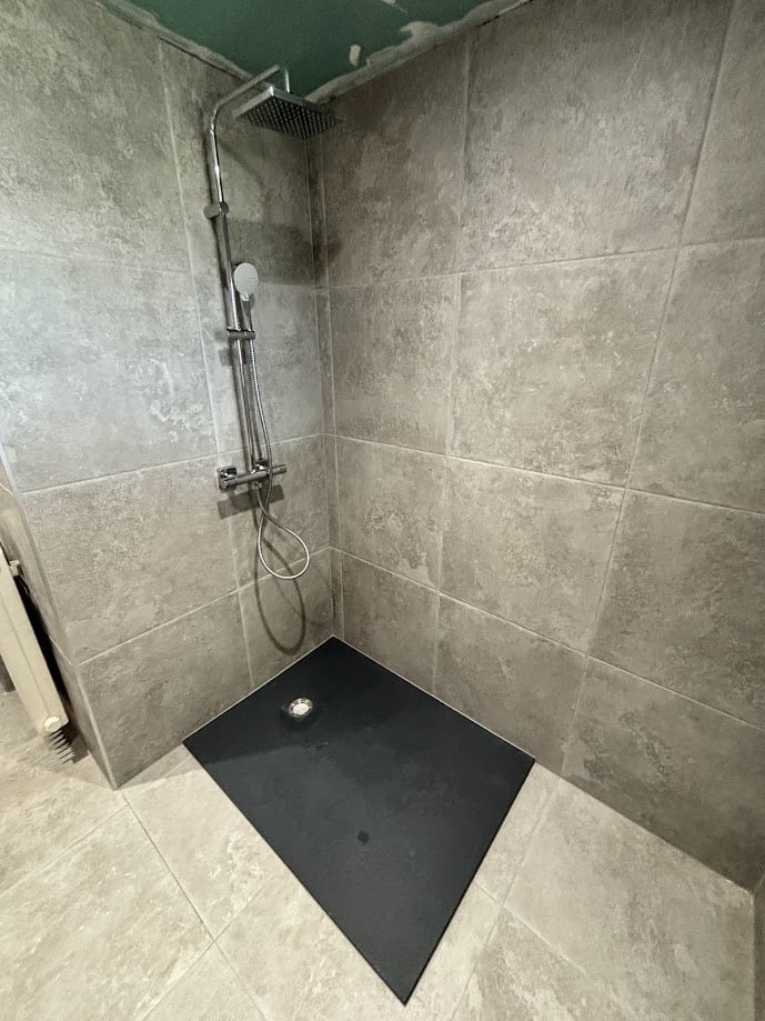 Bac de douche noir en cours d’installation dans salle de bain rénovée