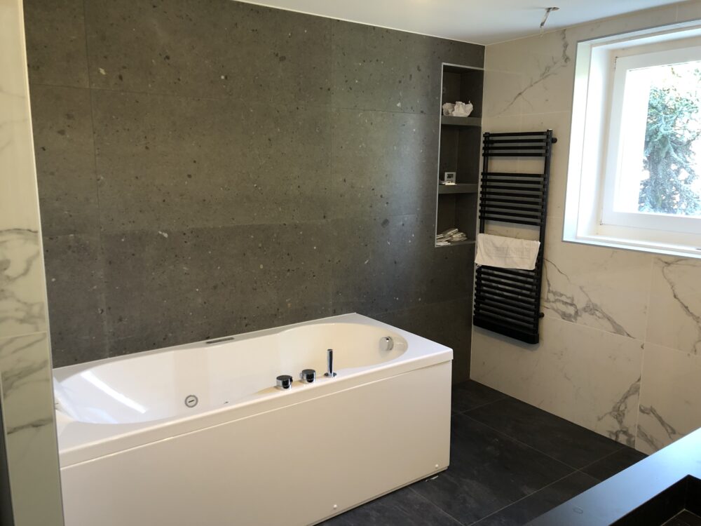 Baignoire balnéo dans une salle de bain moderne avec mur noir effet granit