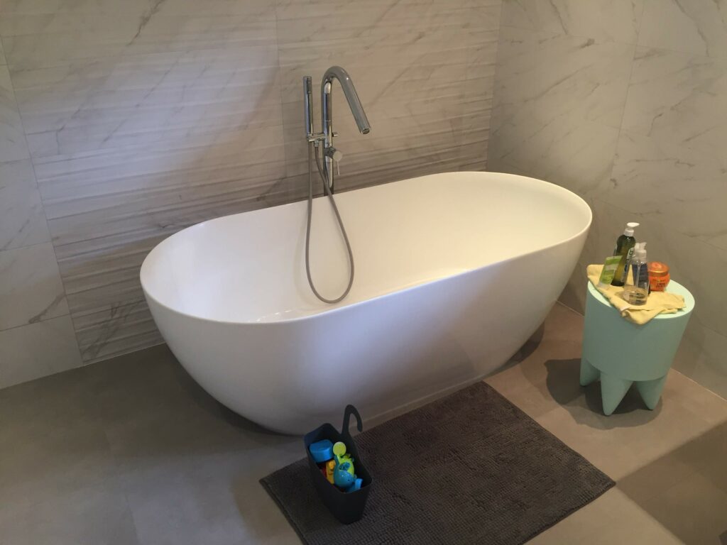Baignoire îlot design avec carrelage mural imitation marbre blanc.