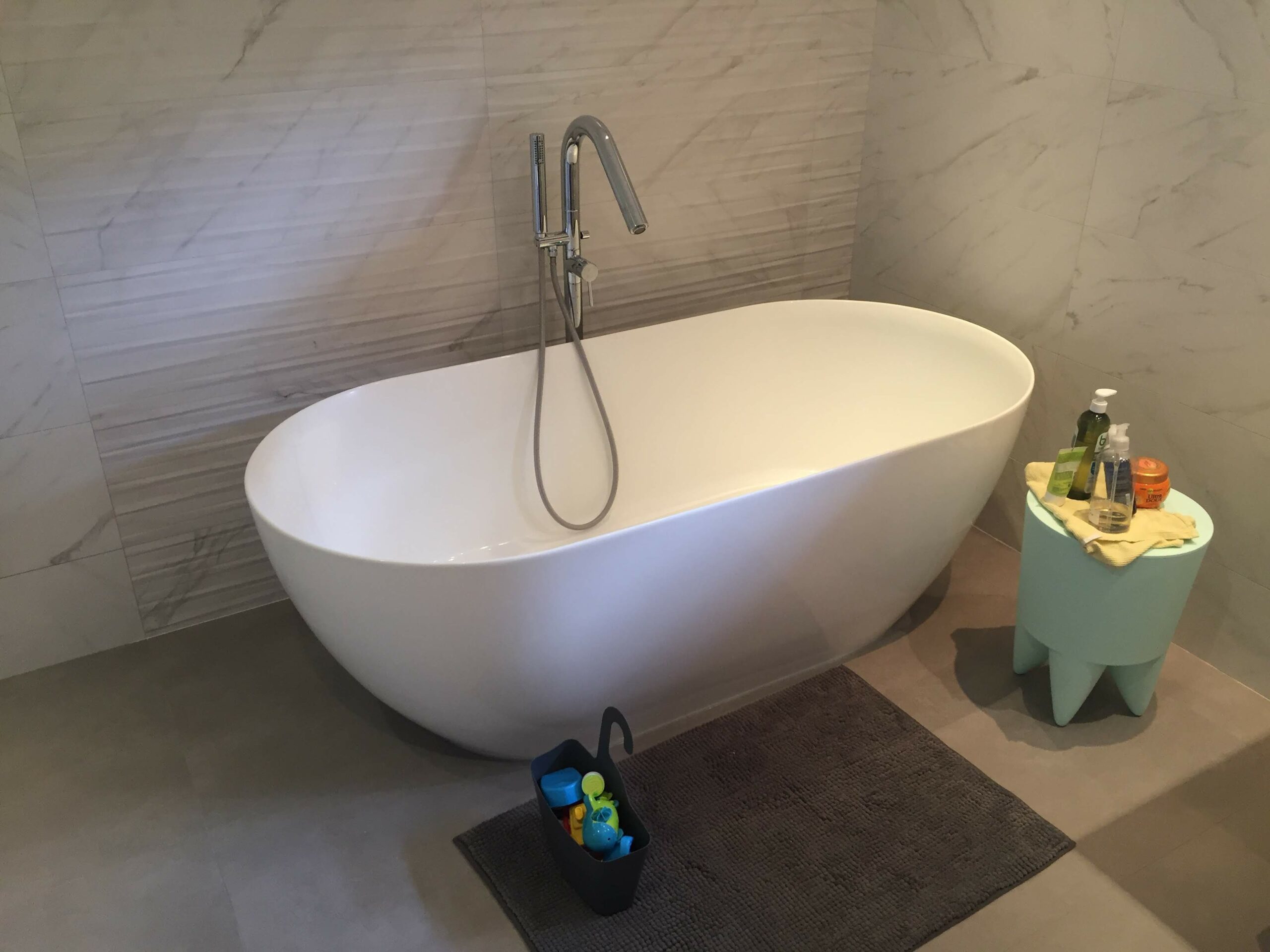 Baignoire îlot design avec carrelage mural imitation marbre blanc.
