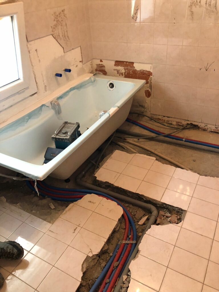 Baignoire démontée et carrelage cassé pour le passage des canalisations.