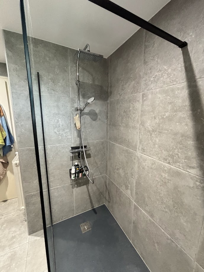 Douche moderne avec robinetterie chrome et carrelage gris effet pierre