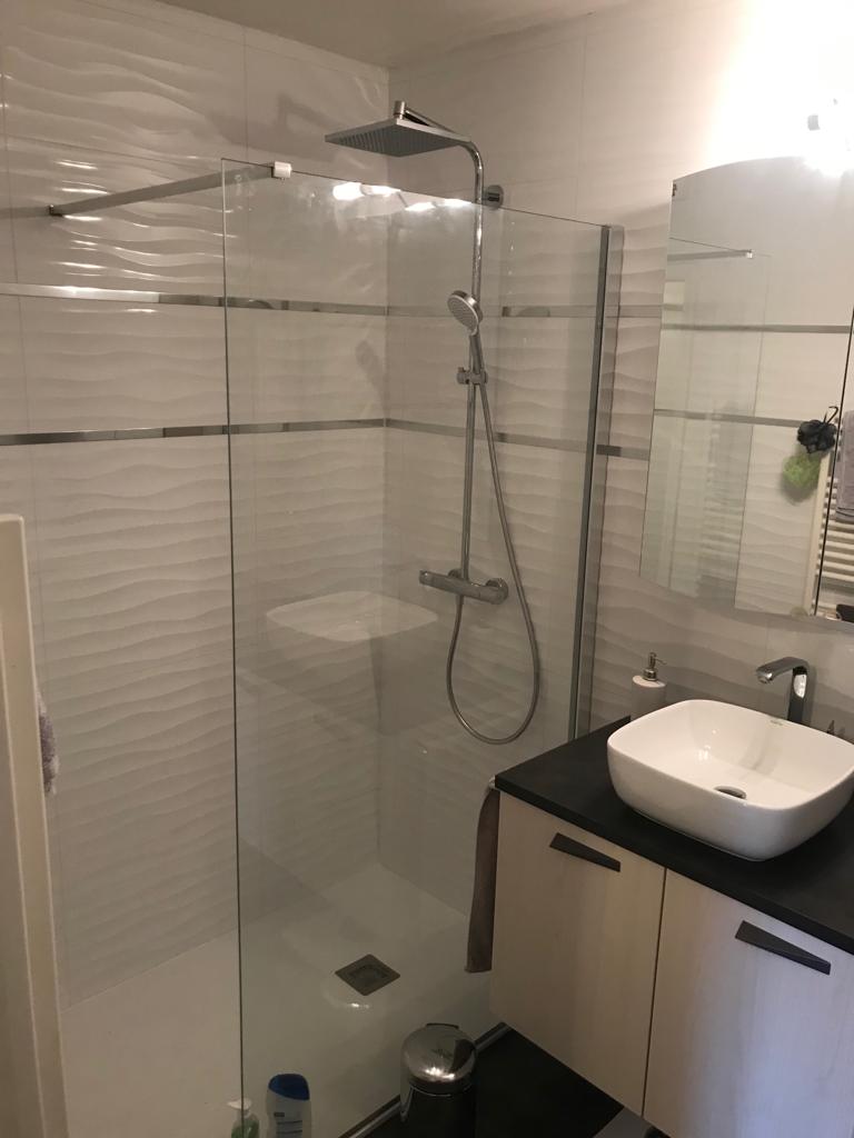 Douche vitrée avec carrelage blanc 3D et colonne de douche moderne.
