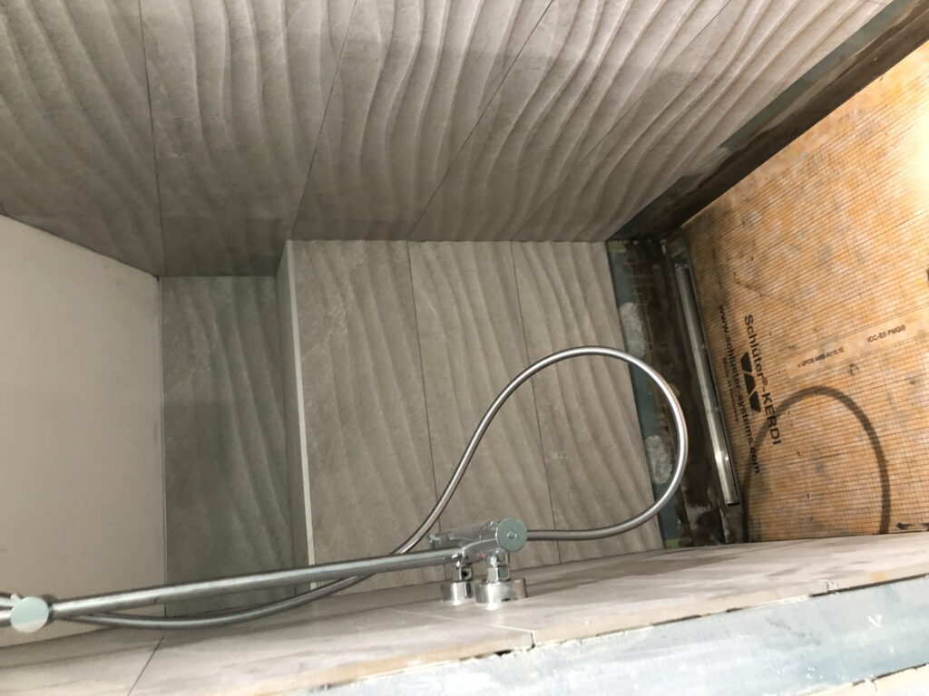 Habillage de baignoire et mur de douche avec carrelage structuré dans une salle de bain à Douvaine.