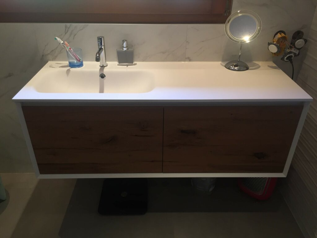Meuble vasque suspendu en bois avec carrelage mural effet marbre blanc.