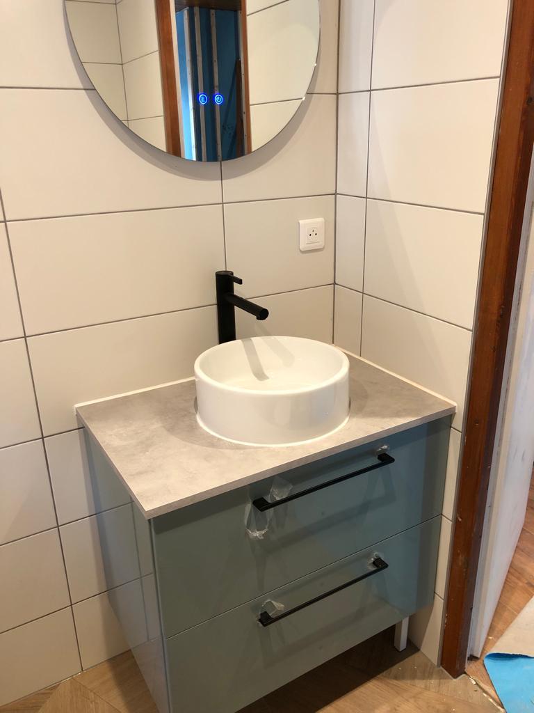 Meuble vasque moderne avec robinet noir mat et miroir rond dans salle de bain rénovée à Châtel