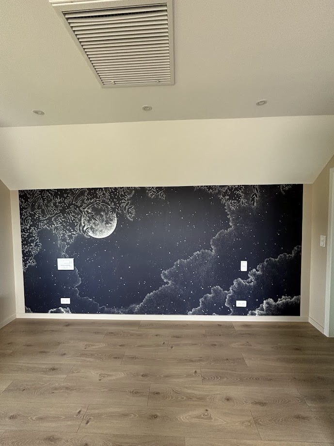 Mur décoré avec une fresque de nuit étoilée et lune dans une chambre rénovée.