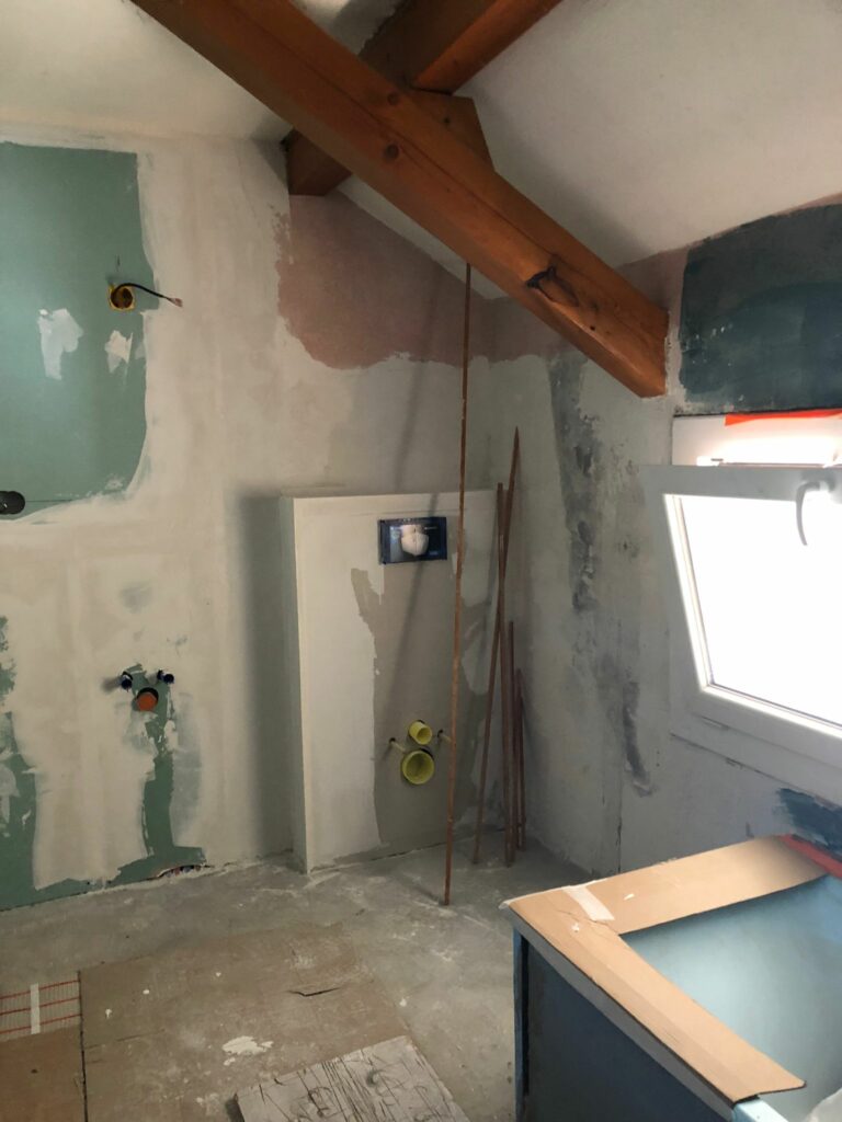 Mur préparé pour carrelage dans une salle de bain sous pente avec poutre apparente.