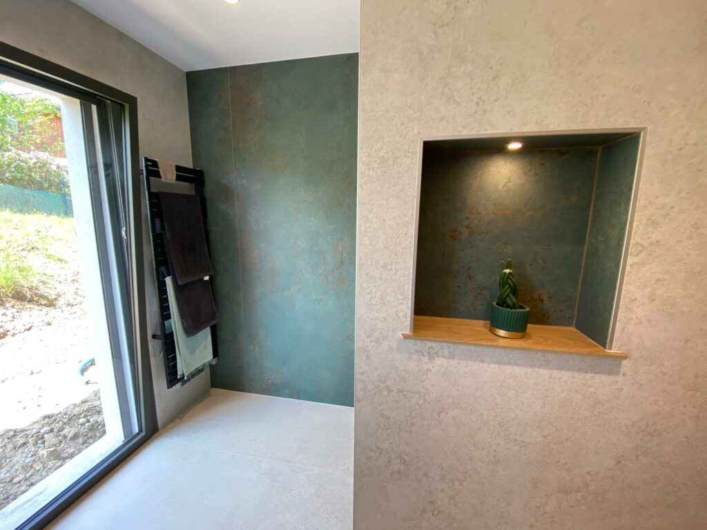Vue de salle de bain avec niche murale et mur en carrelage vert effet rouille.