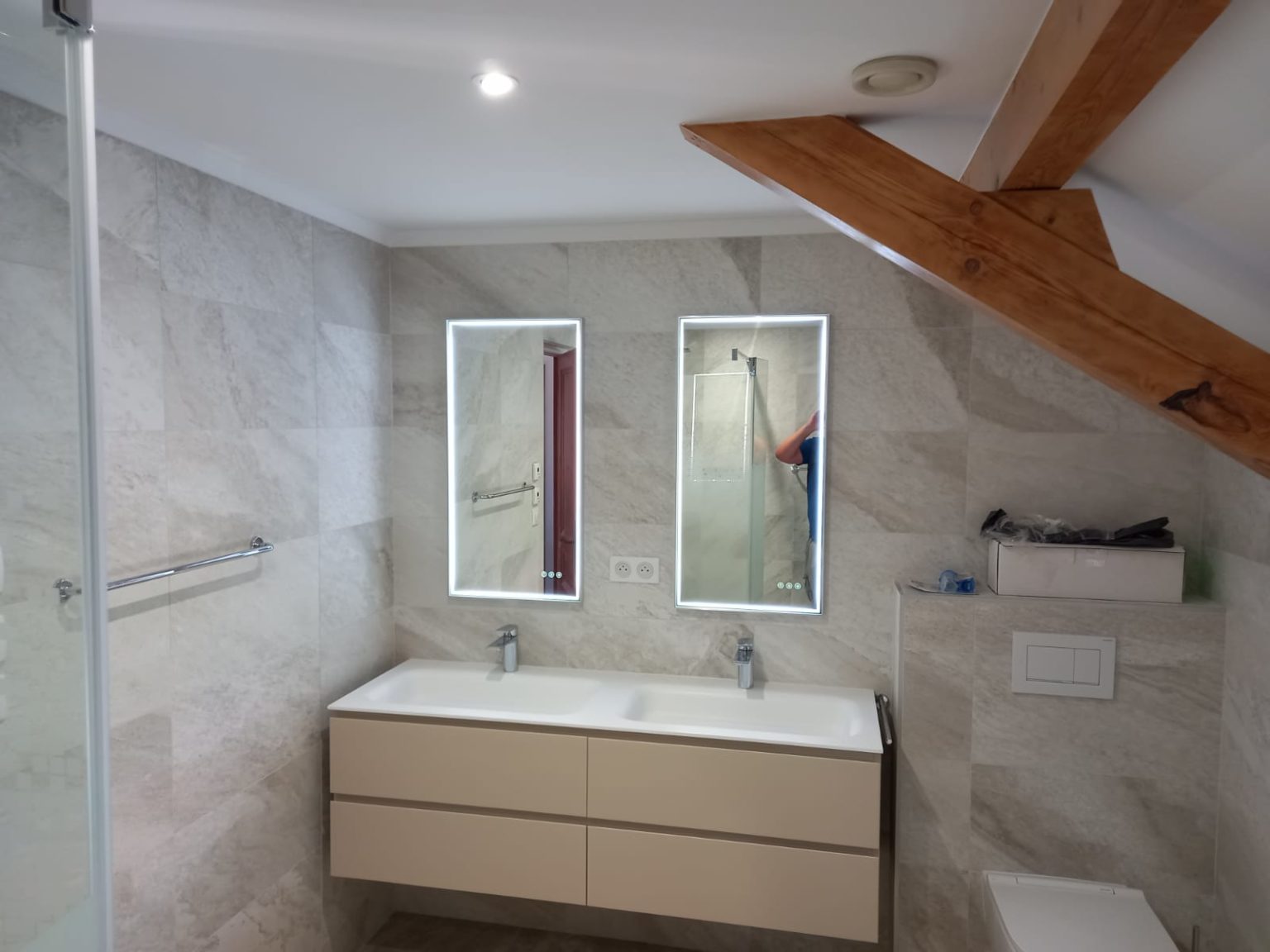 Salle de bain rénovée avec double vasque suspendue et carrelage effet pierre.
