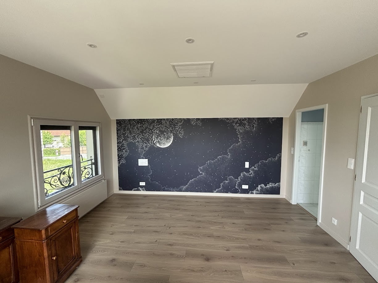Chambre rénovée avec mur décoratif représentant la lune et sol en parquet.